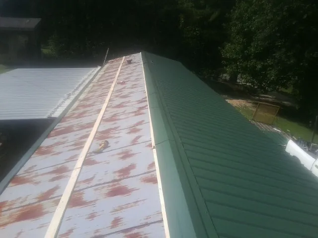 Old rusted panels beside newly installed green metal roofing — Wind Damage Roof Repair by Roofing Brothers in Dickinson