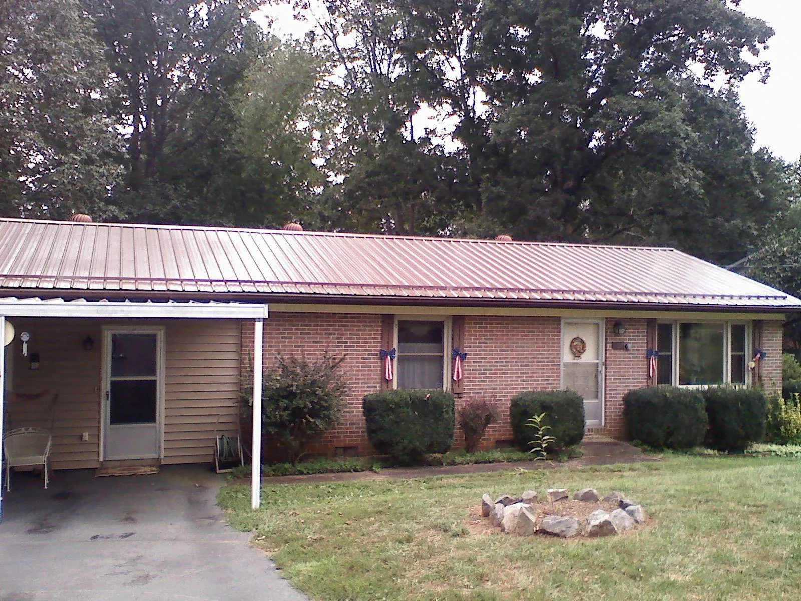 Bronze metal roof and carport on a brick ranch home — Roof Repair work by our crew in Dickinson